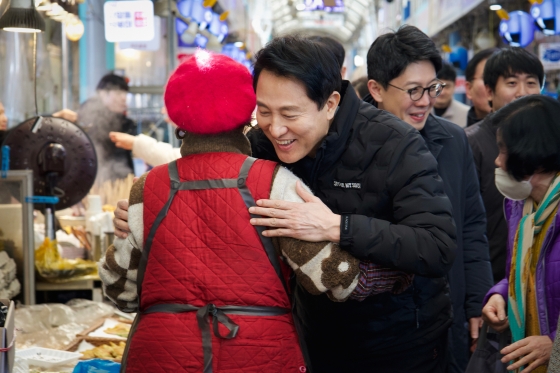 사진7. 오세훈 서울시장이 설 연휴 첫날인 25일(토) 중곡제일골목시장을 방문해 상인을 따뜻하게 포옹하며 설 인사를 건네고 있다.