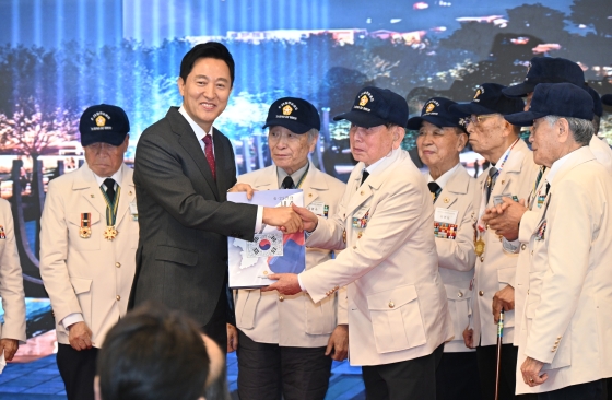 사진3. 3일(월) 열린 _세종로공원 및 상징조형물 조성 설계공모 당선작 시상식_에서 오세훈 서울시장이 참전용사로부터 도서(6.25 전쟁, 내가 나라를 지켰다)를 기증받고 있다